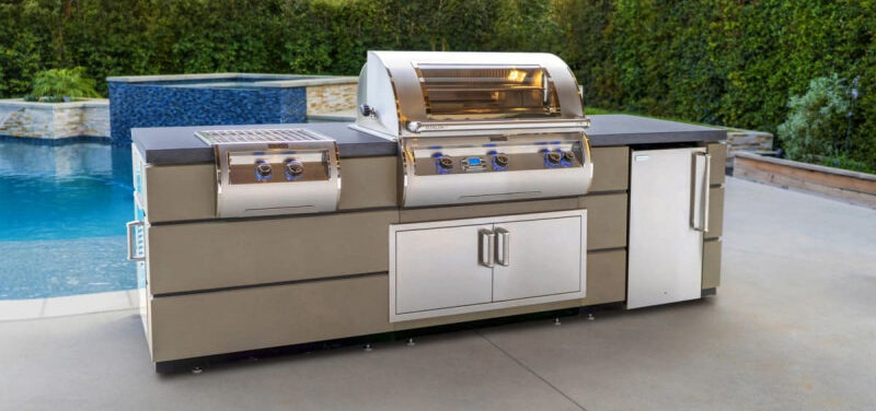 An outdoor kitchen island with a grill, a built-in fridge, warming drawers, and an extra set of burners