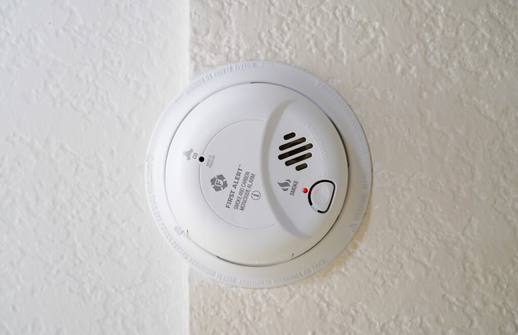 A smoke alarm on a brightly lit ceiling, working as a part of a modern security system.
