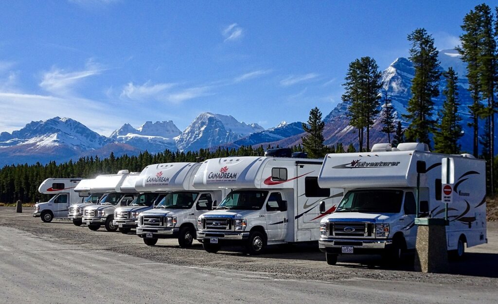 A row of seven RVs in a national park by snowy mountains