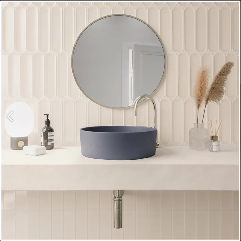 White curved brick tile backsplash behind a mirror and blue ceramic sink basin