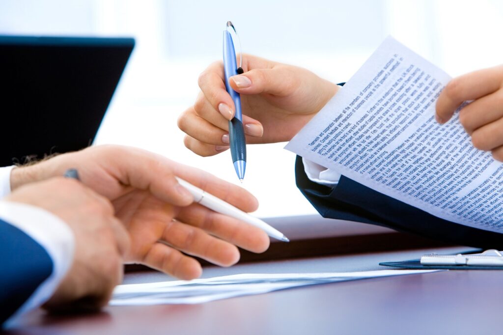 A licensed contractor signing paperwork with their client at a desk