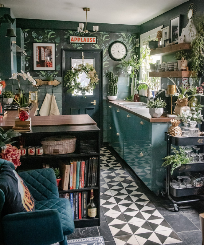 Maximalist kitchen with dark green walls and counters, and a patterned black and white triangle tile flooring