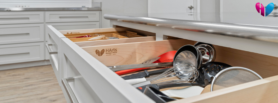 Two soft-close drawers, open to show kitchen utensils and our HArts Design+Build engraving